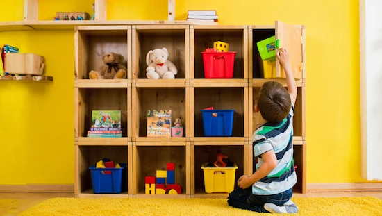 Child organizing toys and books in colorful cube storage units, creating a versatile diy kids storage shelf.