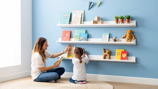 Mother and daughter organizing books on floating shelves, showing a diy kids storage shelf for small spaces.