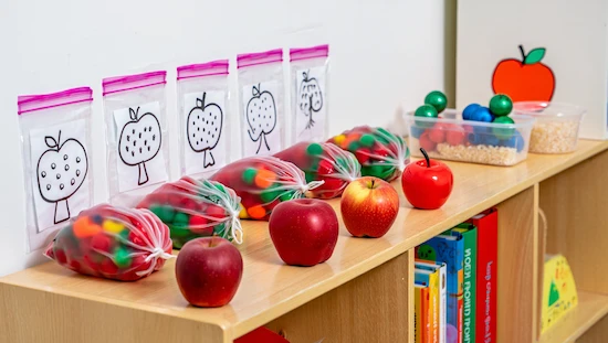 Apple crafts for preschoolers sensory bag station with ziplock bags, apples, colorful pom-poms, and classroom materials, no words
