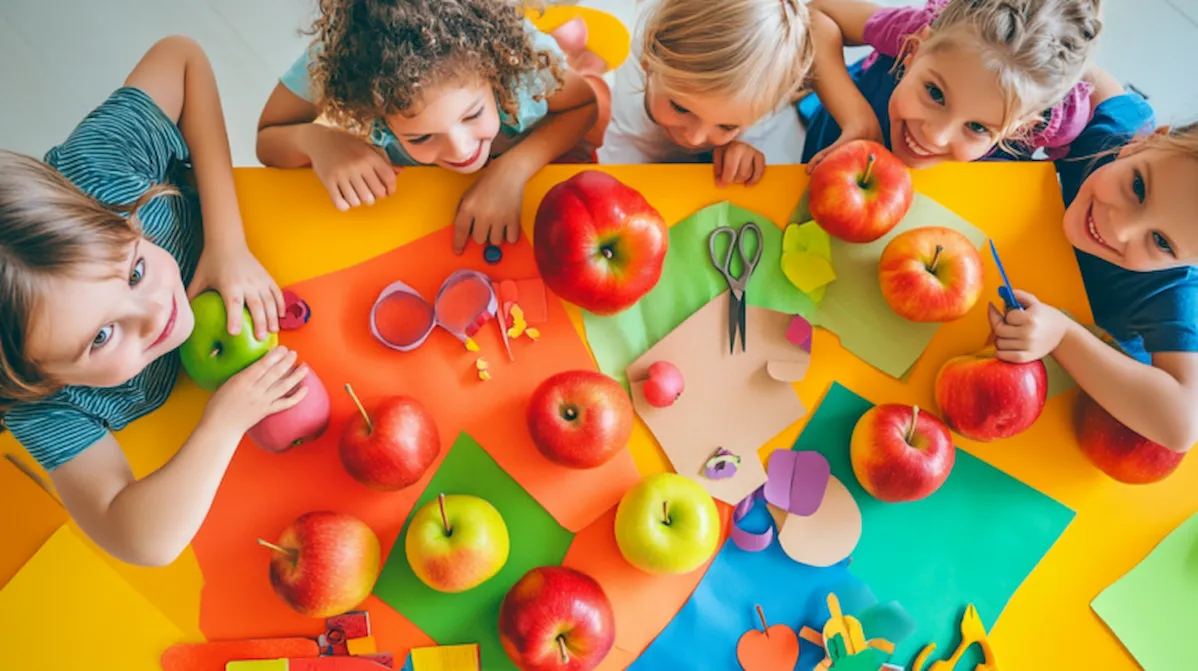 Apple crafts for preschoolers – kids with apples and colorful craft materials at a bright table