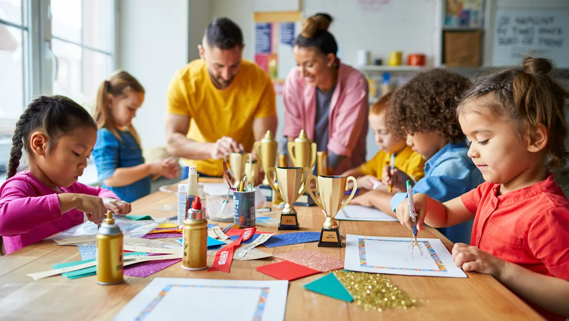 Children and adults working together on award diy crafts, making trophies, ribbons, and certificates at a colorful craft table