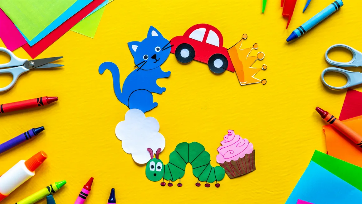 Bright, colorful letter c crafts for preschool, featuring a cat, car, caterpillar, cloud, cupcake, and crown made from paper, with craft supplies on a yellow background.