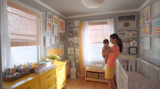 A mother holding her baby in a nursery decorated with upcycled and budget-friendly diy nursery projects, featuring baskets, art, and handmade storage