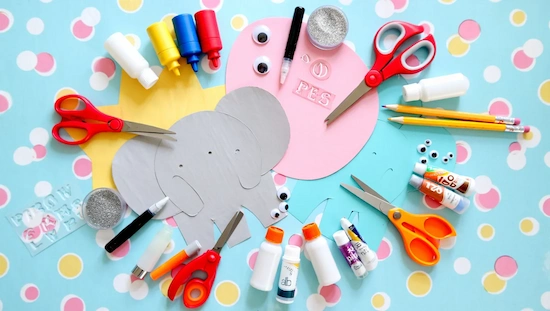 Colorful craft supplies including scissors, glue, googly eyes, and paper shapes for easy and fun preschool letter E crafts.