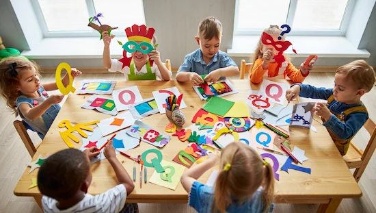 Children making letter q crafts for preschoolers with colorful paper, masks, quilts, and creative Q shapes at a lively classroom table.