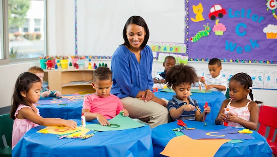 Integrating letter c crafts for preschool into the curriculum—preschool teacher and children creating letter c crafts with colorful supplies and a “Letter C Week” board.