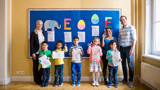 A classroom display of Letter E crafts with children, parents, and a blonde teacher smiling together.