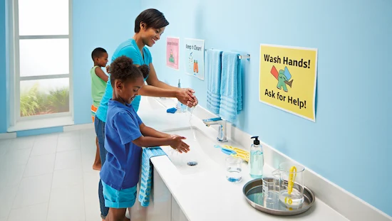 Parent and children wash hands after diy potions for kids activity, with clean utensils and safety signs in a bright, modern bathroom.
