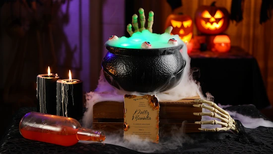 Easy DIY cauldron centerpiece for Halloween parties with spooky decor, glowing lights, skeleton hand, candles, and pumpkin decorations.